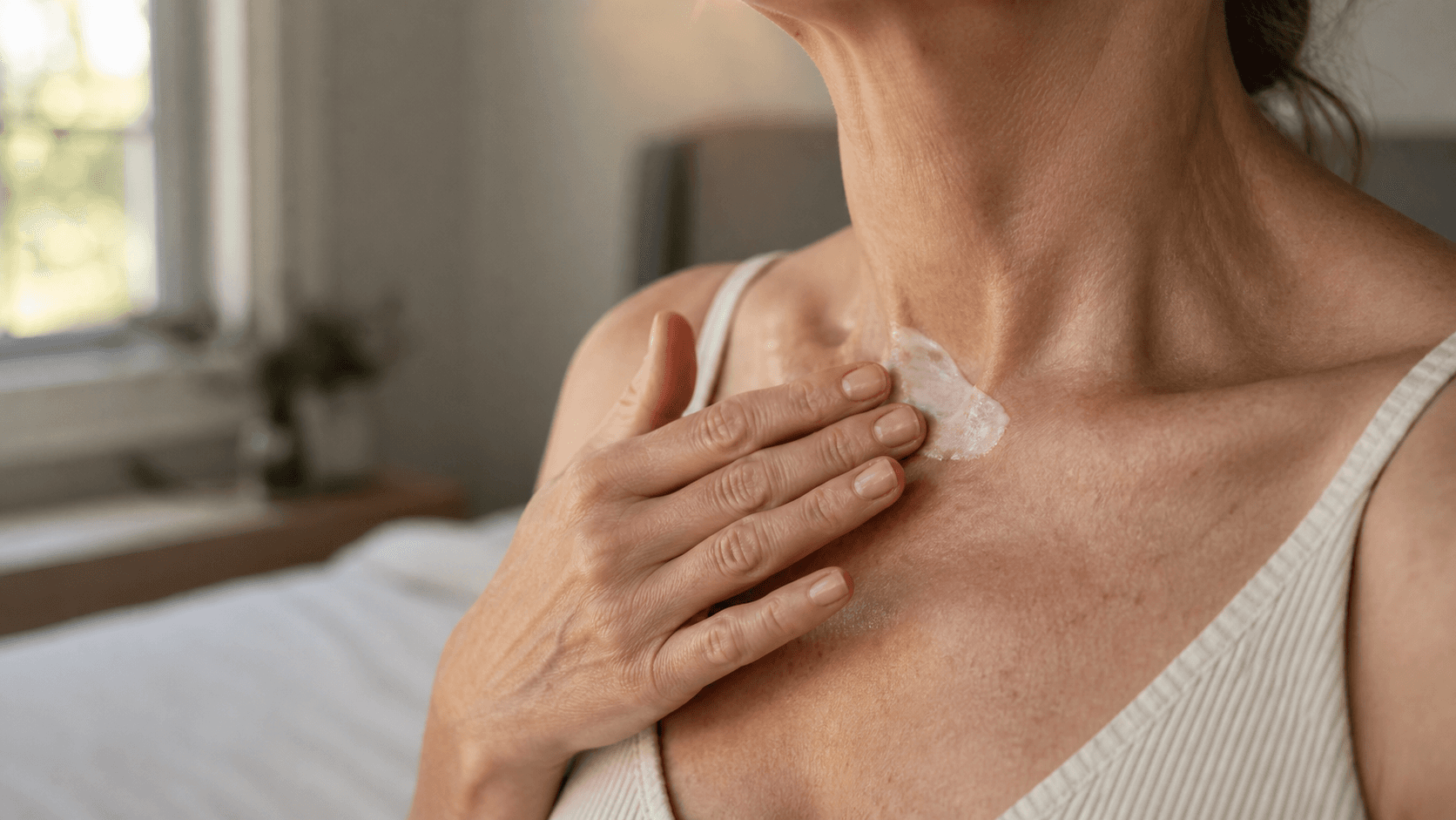 Mulher madura aplicando hidratante no pescoço e colo em luz suave